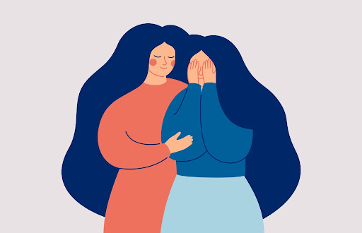 One woman comforting another as she covers her face, overcome with anxiety